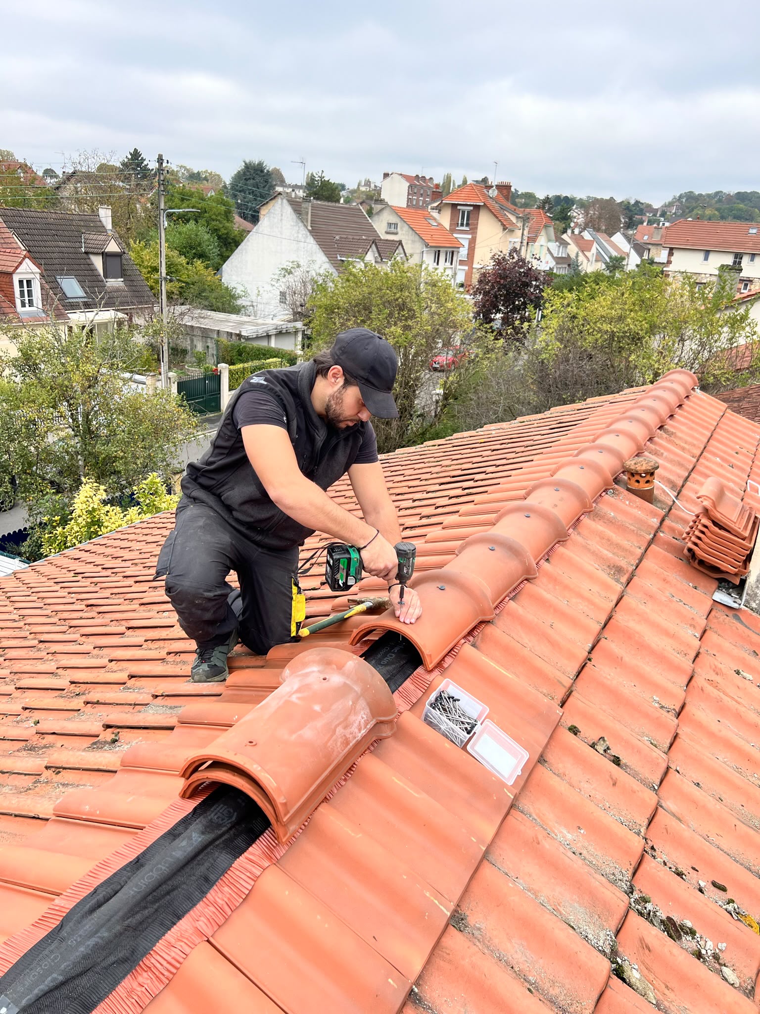 Pose de tuiles de faîtage par un couvreur à Pontoise